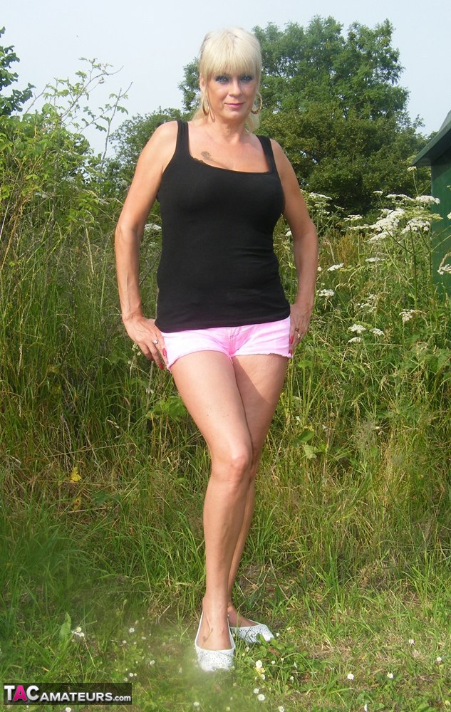 Blonde MILF Dimonty gets naked in footwear near some trees and bushes